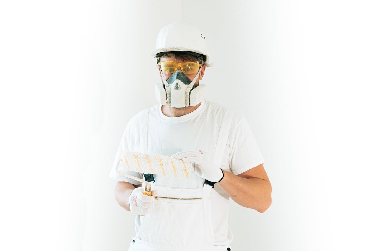 Hello world! A professional painter wearing safety gear holding a paint roller, ready for work.