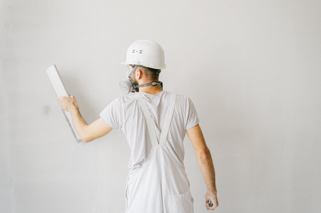 The Art of Drawing Readers In: Your attractive post title goes here Back view of a construction worker in safety gear plastering a white wall.